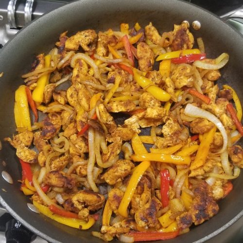 Skillet full of chicken fajita with onions and peppers
