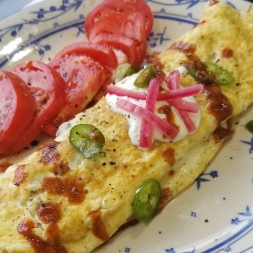 Mexican omelette garnished with onion and sour cream
