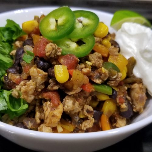 Southwest turkey skillet with ground turkey, corn, black beans, rotel, jalepenos, sour cream, cilantro, green chilis, sour cream, and lime wedge