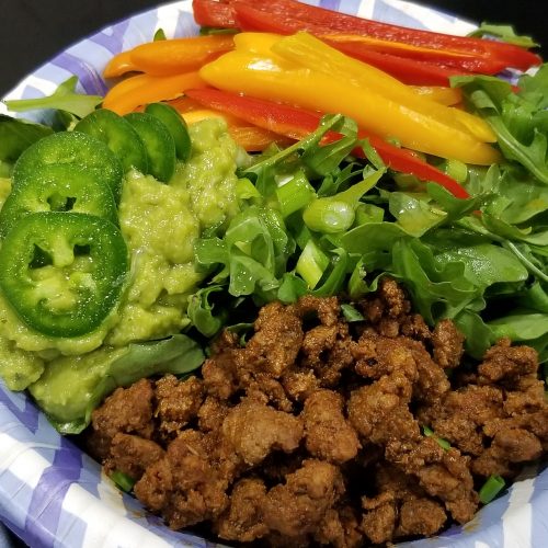 Taco seasoned ground beef served on arugula with sliced bell peppers, guacamole, jalepenos, and lime juice