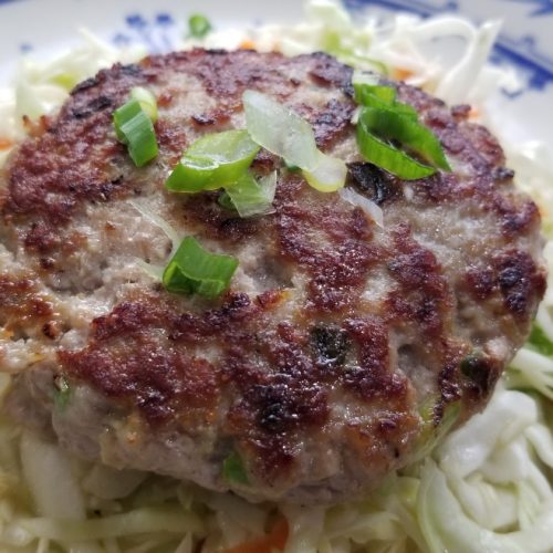 Asian pork burgers with garlic, ginger, scallion on top of slaw with aminos and rice wine vinegar