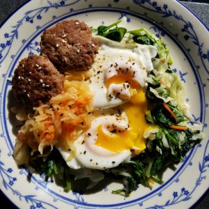 Sauteed spinach and kale with pork sausage patties, over easy eggs with runny yolk, and kimchee