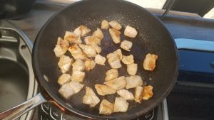 Cubed chicken breast in an 8" skillet with cooking oil